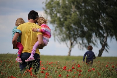 男人抱着女孩在红花地上